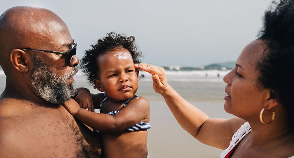 Woman putting sunscreen on small child's face on a beach