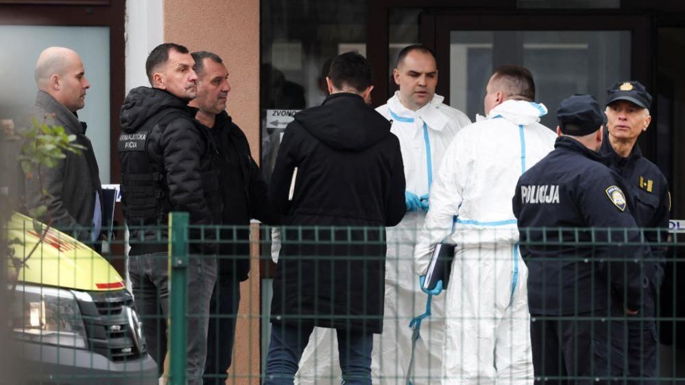 Police officers and forensic officers stand outside the school in Zagreb