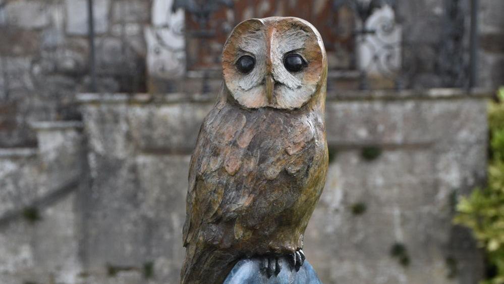 A brown owl sculpture looking at the camera