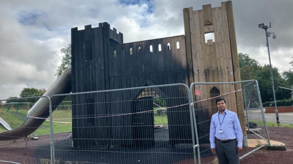 A man standing next to wooden play equipment  