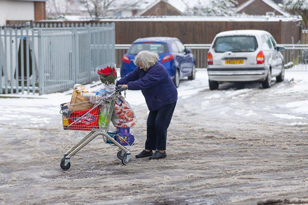 A woman struggles with a shopping trolley