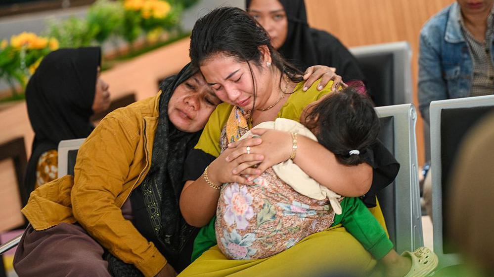 A woman comforts another woman holding a baby