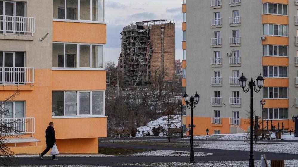 A damaged block of flats behind two new blocks built by Russia's occupying forces in February 2025
