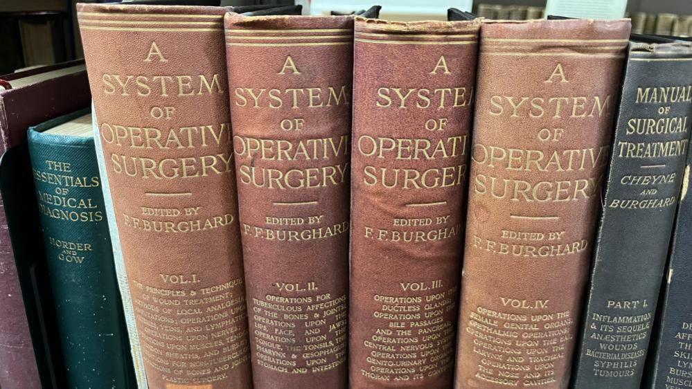 A row of old medical books, including four volumes of A System of Operative Surgery.