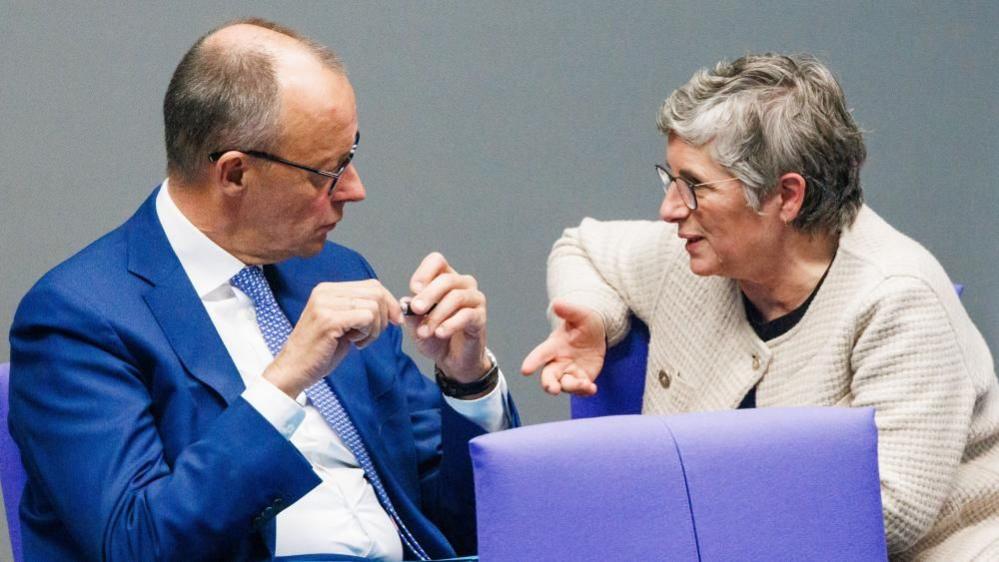 Friedrich Merz of the Christian Democrats talks to a Greens MP in the German parliament