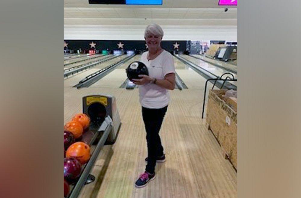 A photo of Julie at the bowling alley. Julie is holding a bowling ball