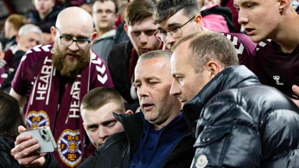 Hearts fans watch on their phones