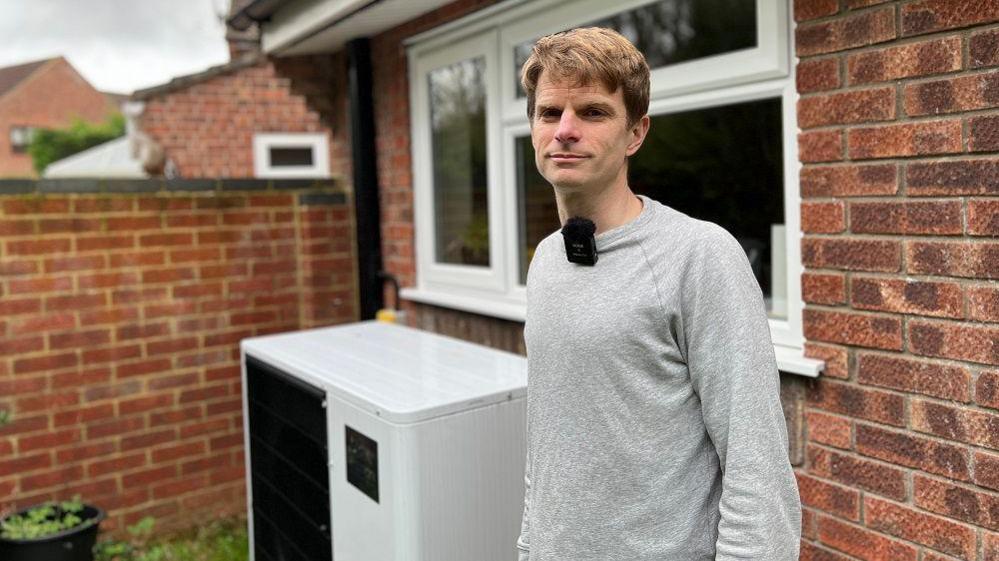 James Bradbury stands in front of a heat pump