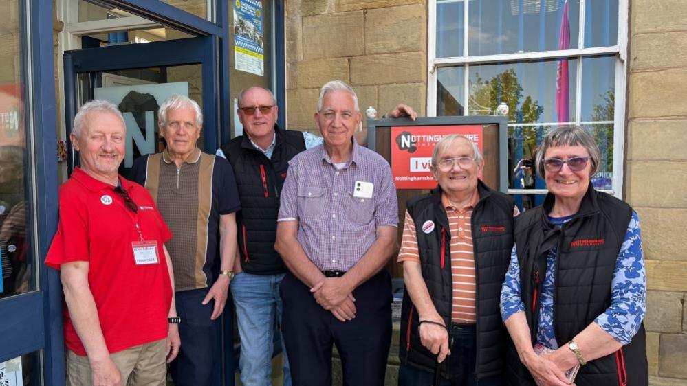 Volunteers of the Nottinghamshire Mining Museum stood outside its main entrance, smiling at the camera.