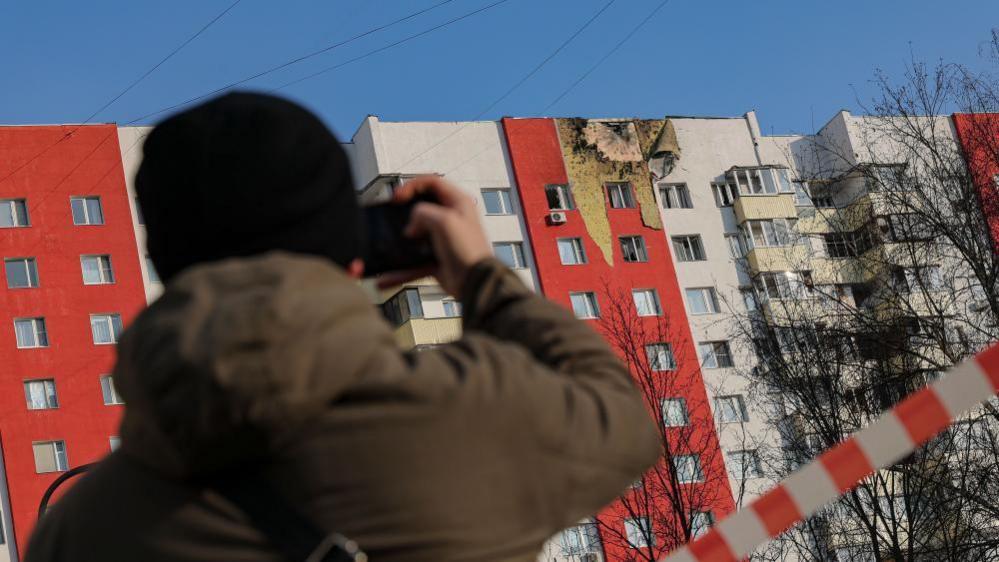 A man takes a photo of a building in Moscow which was hit by a drone attack in March 2025.