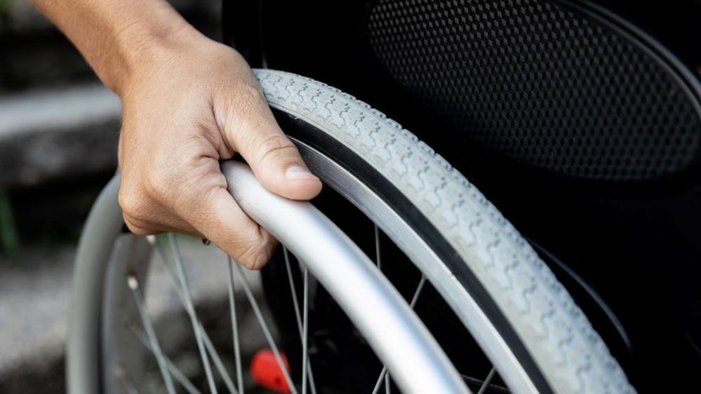 Hand gripping rail on wheelchair 