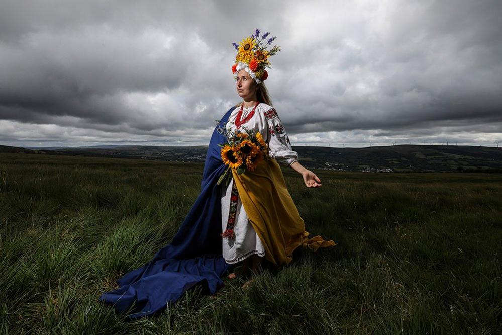 Stood barefoot, in a traditional Ukrainian embroidered dress and Vinok, proudly draped in the Ukrainian flag, Olha Boyko, celebrates Ukraine Independence Day