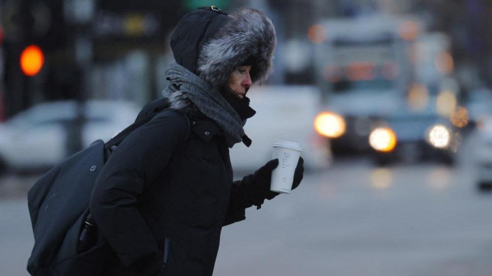 A woman in Boston is bundled up as she walks down the street on 3 January 2023, amid a deep freeze warning in New England