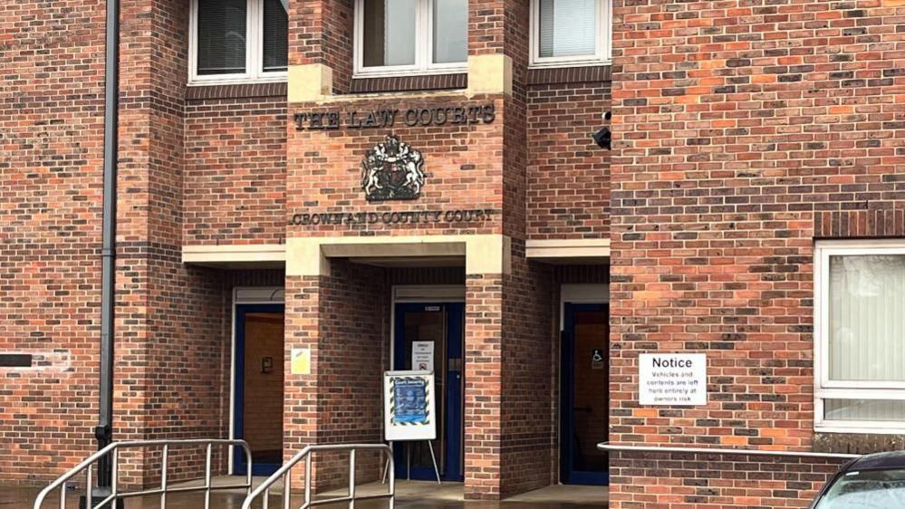 Norwich Crown Court is a red brick building, with stone lintels and steps, with chrome hand rails to the staircase. The Royal Crest is mounted above the main entrance door.