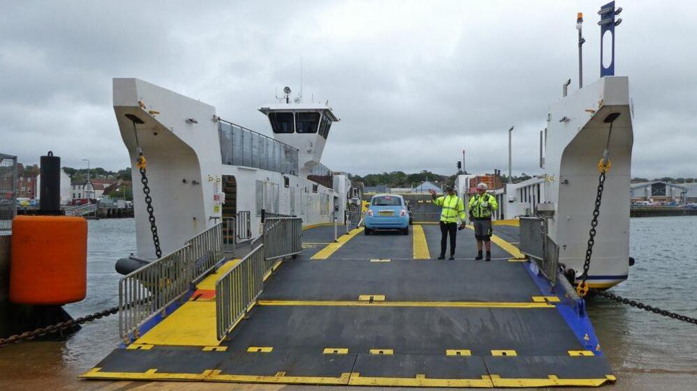 View of driving on to floating bridge with two staff on the ramp