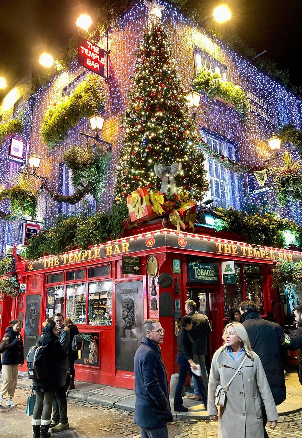 People outside a pub that is covered in Christmas decorations