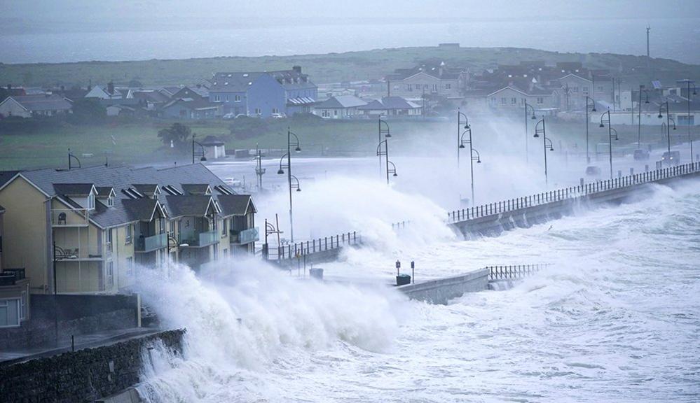 Waves lash the Irish coast, spraying buildings and a road