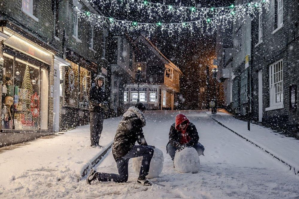 Revellers roll giant snowballs in the first snow of this winter to fall on Saffron Walden, in Essex