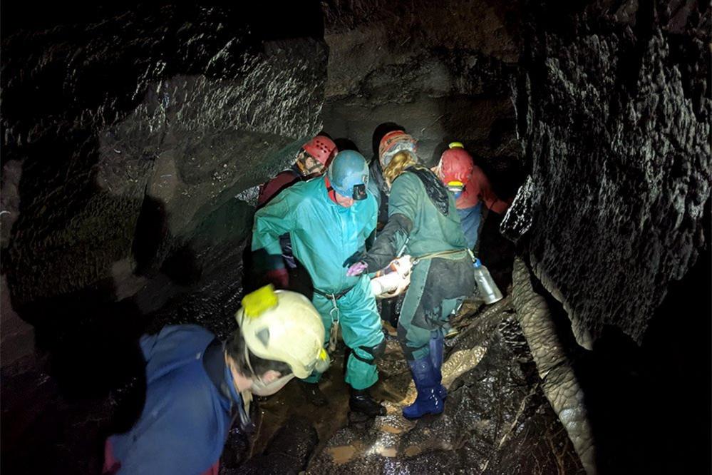 Rescue team carrying injured caver on a stretcher through a cave, 8 November 2021