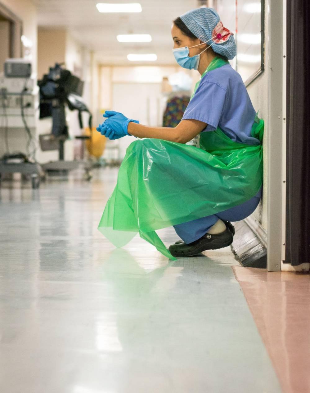 A medic crouching down in a hospital corridor