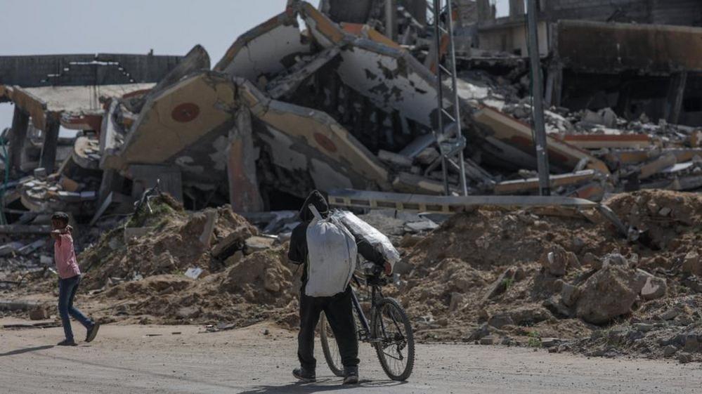 A displaced Palestinian man pushes a bike along Salah al-Din road in southern Gaza after fleeing Rafah (9 May 2024)