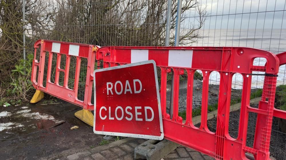 Road block barrier and closure sign on the edge of the cliff at Beach Road in Happisburgh.