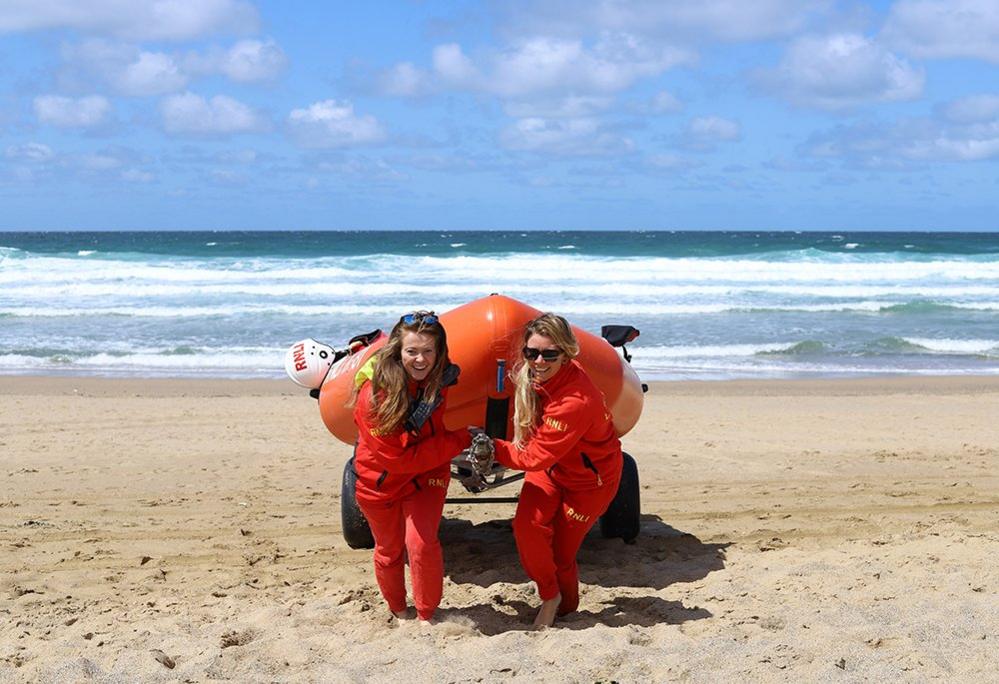 Women pull a lifeboat up the beach