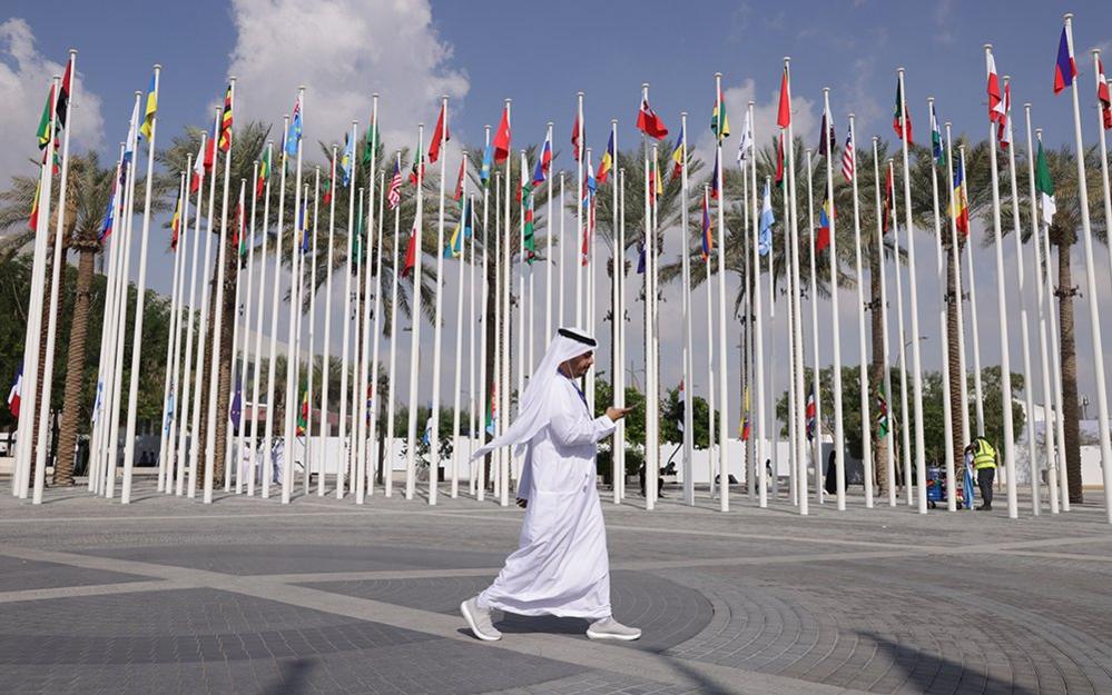 A man walks past flags outside the site of COP28 in Dubai on 29 November