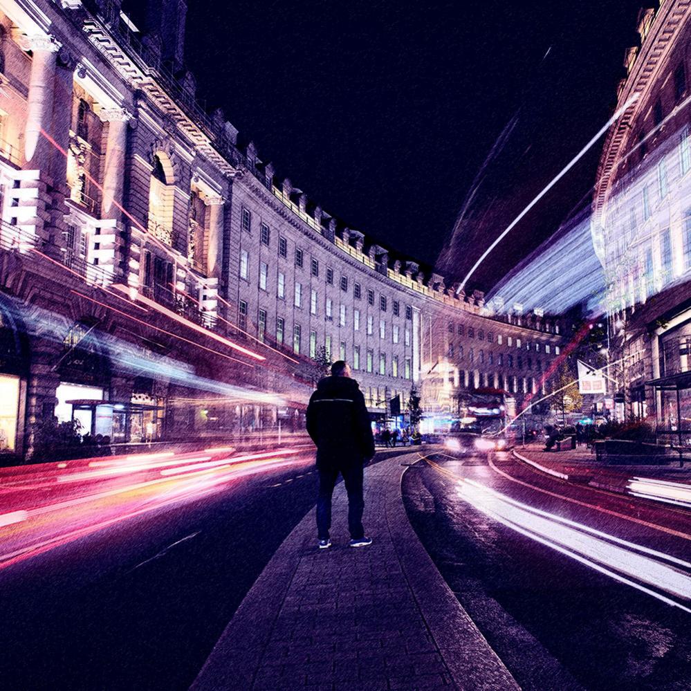 Man in Regent Street with lights of cars blurring past him