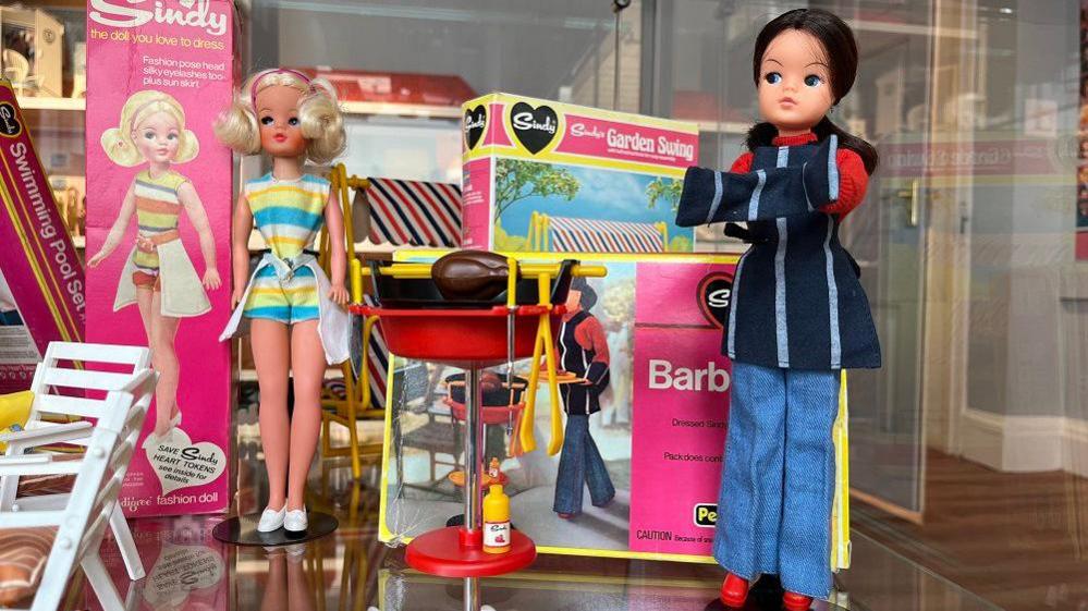 A Sindy dolls next to a barbecue accessory