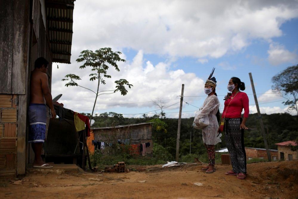 Vanderlecia and Natalina wear protective masks as they talk to a neighbour outside of his home