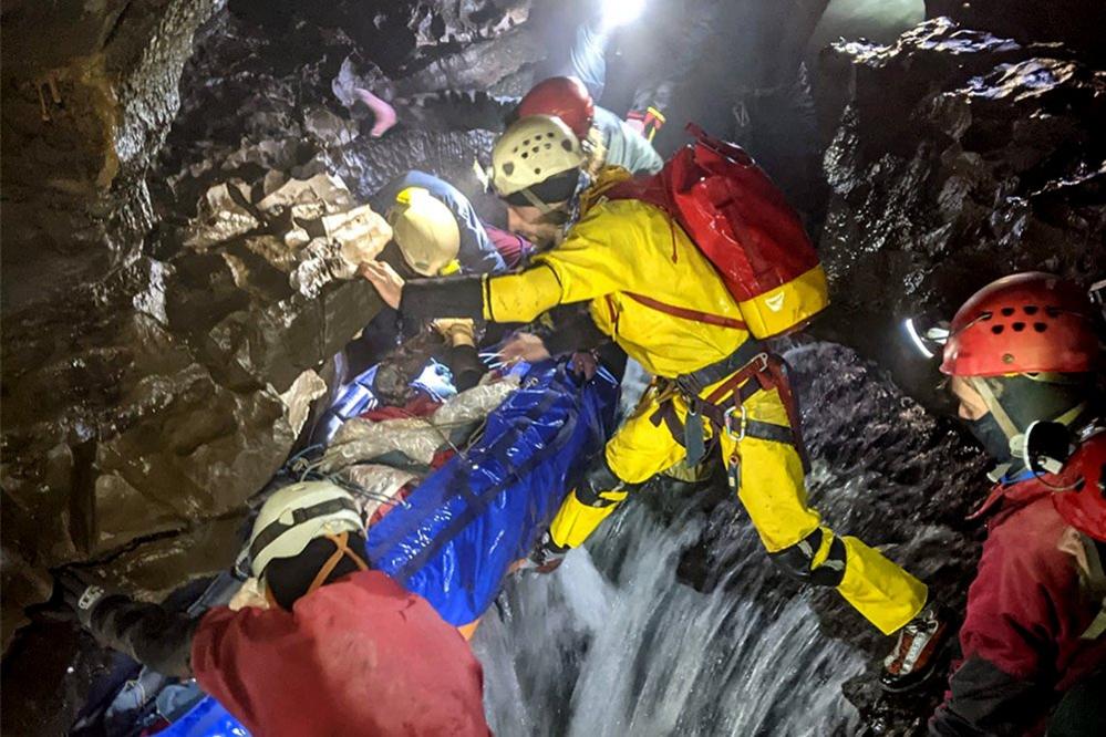 Rescue team carrying injured caver on a stretcher through a cave, 8 November 2021