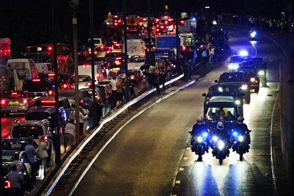 People get out of their cars to watch as the hearse carrying the coffin of Queen Elizabeth II passes along the A40 in west London, 13 September 2022