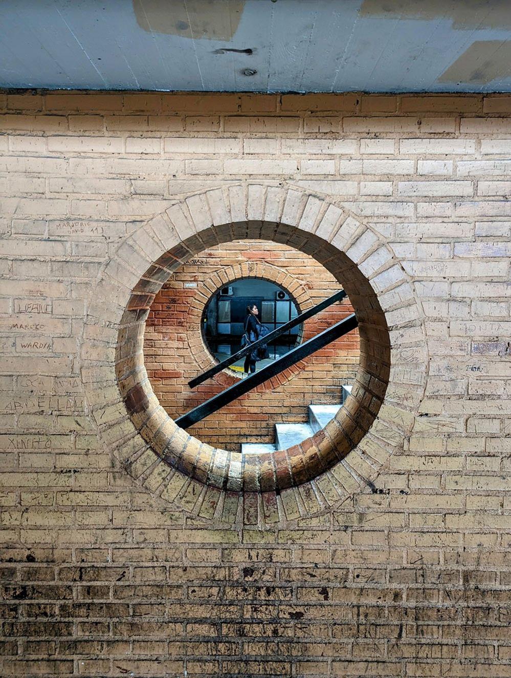 Figure seen through a round window at Seville bus station