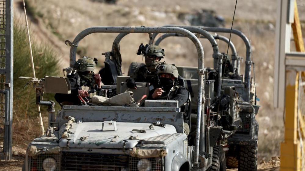 A military jeep with several masked soldiers inside