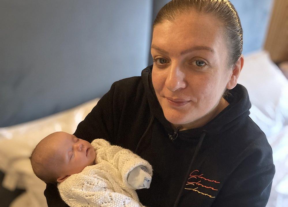 Michaela Ali holding her baby in a hotel room