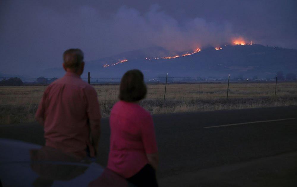 Local residents look at smoke and fire over a hill during wildfires near the town of Medford, Oregon, 9 September 2020