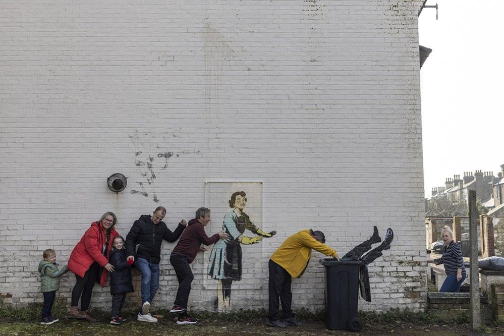 A family do the conga next to a new artwork called Valentine's Day mascara in Margate, Kent, 15 February 2023