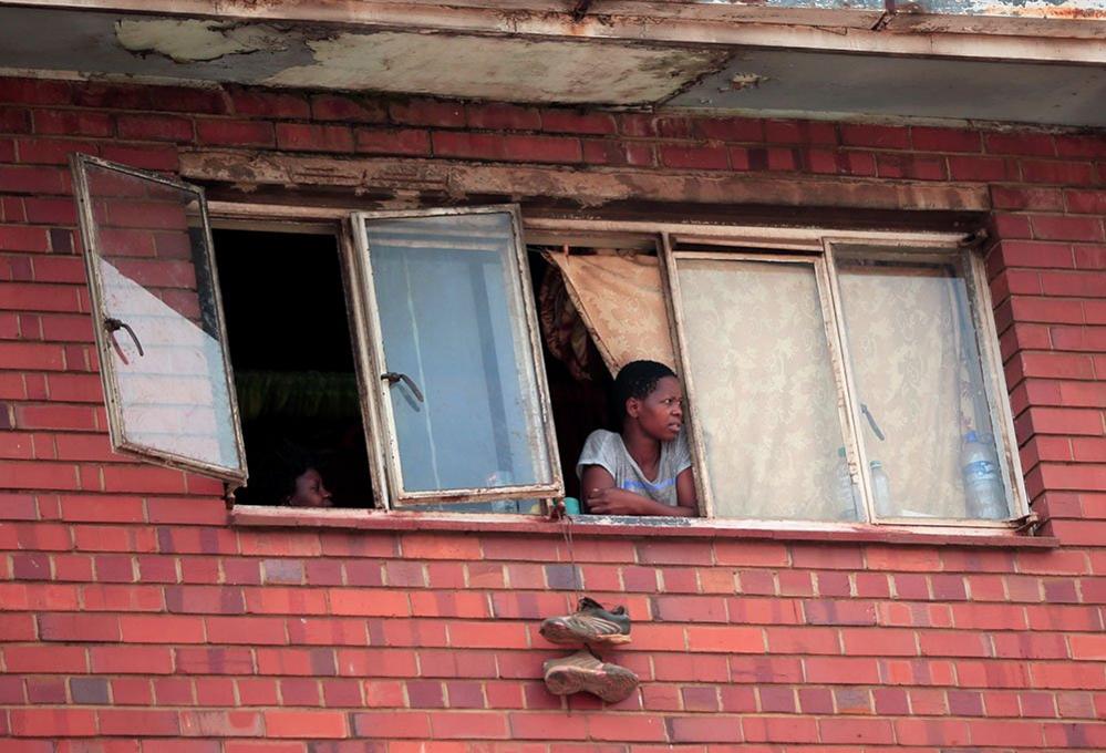 A woman looks out of her window in Harare