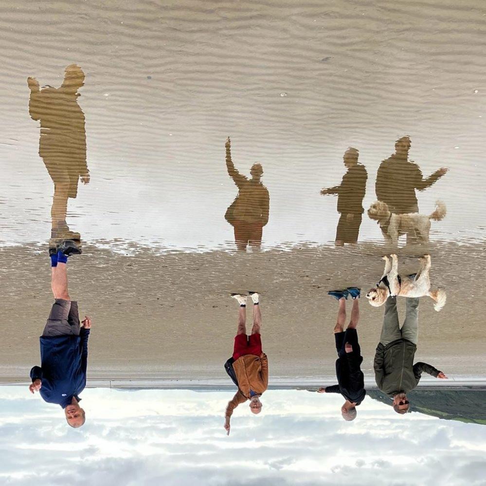 A group of people reflected in the sea