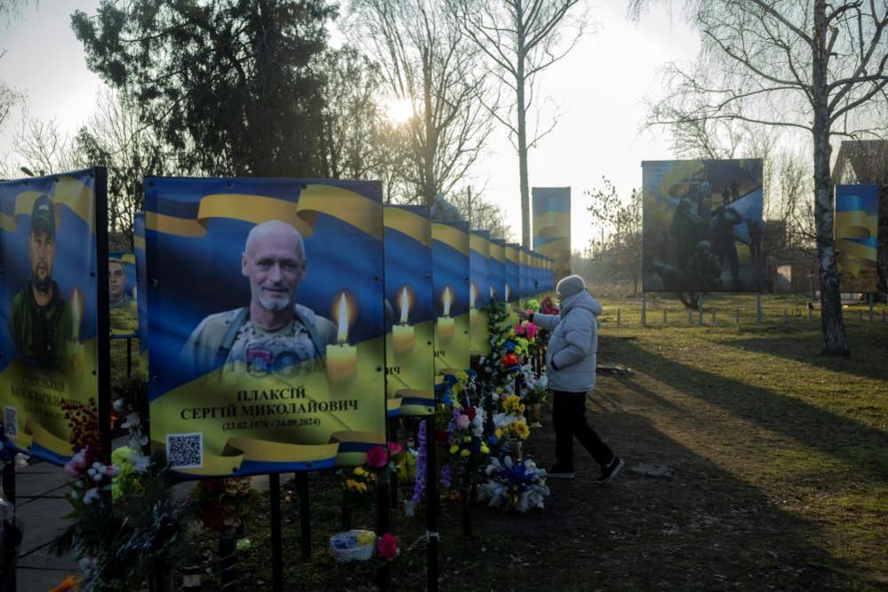 A woman pays her respects at portraits of fallen Ukrainian servicemen in Zavallia, central Ukraine. Photo: 10 February 2025