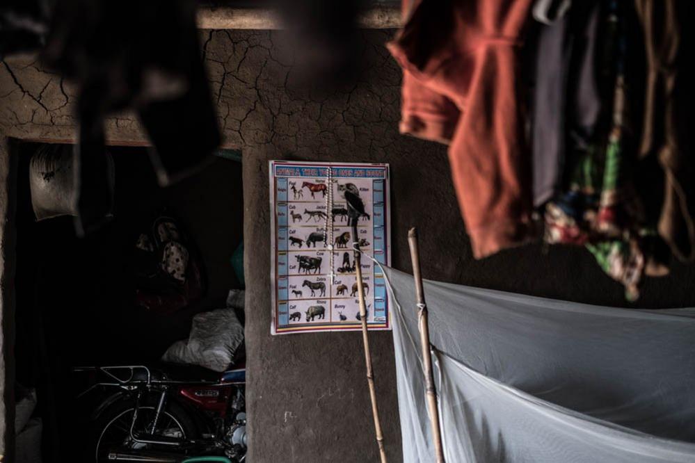 An educational poster hangs on the wall of Lona Kiji's home in Bidi Bidi refugee camp