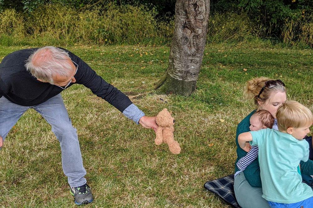 Man showing teddy to his granddaughter