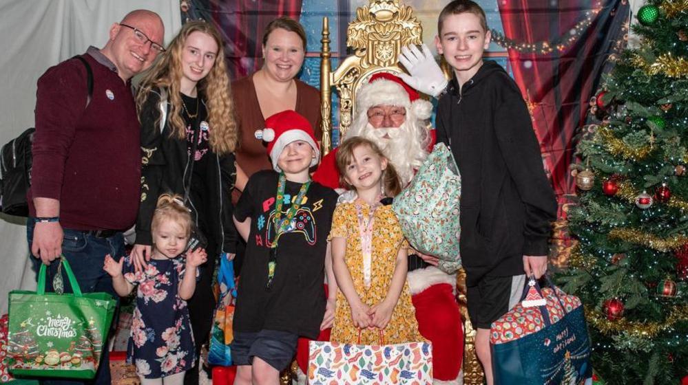 Lilly and Rachel with the Hamer family posing with Father Christmas and presents at the event. Lilly's three other siblings and father are also pictured. 