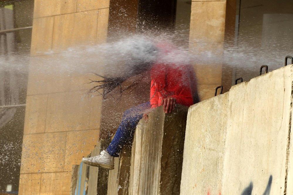 A Lebanese protester is hit with a burst from a water cannon