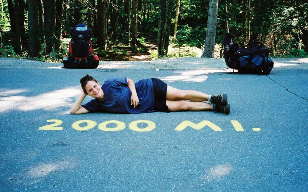 Woman beside a sign that reads 2000 miles