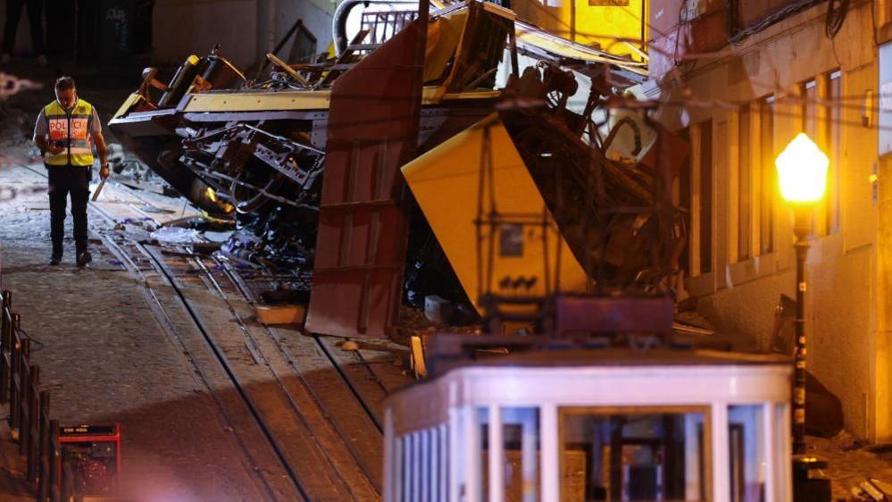 A police officer stand at the scene after the Gloria funicular cable railway derailed in Lisbon