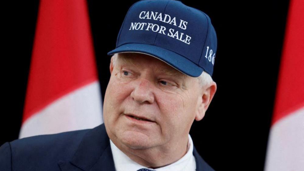 Ontario Premier Doug Ford, wearing a "Canada is not for sale" hat, speaks to journalists at a provincial and territorial leaders meeting in Ottawa, Ontario, Canada January 15, 2025. 