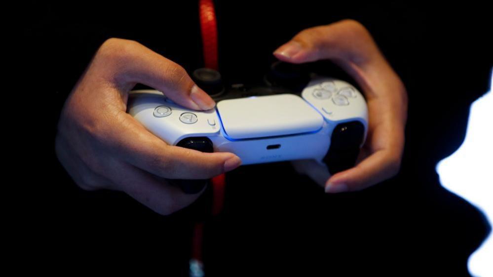 A close up of someone holding a white PS5 controller