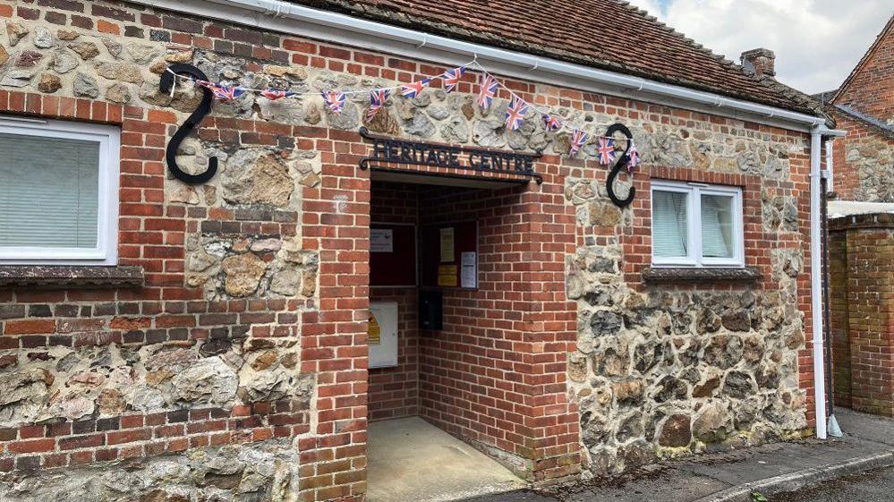 Small stone building with Union Jack bunting and a sign saying it is the heritage centre